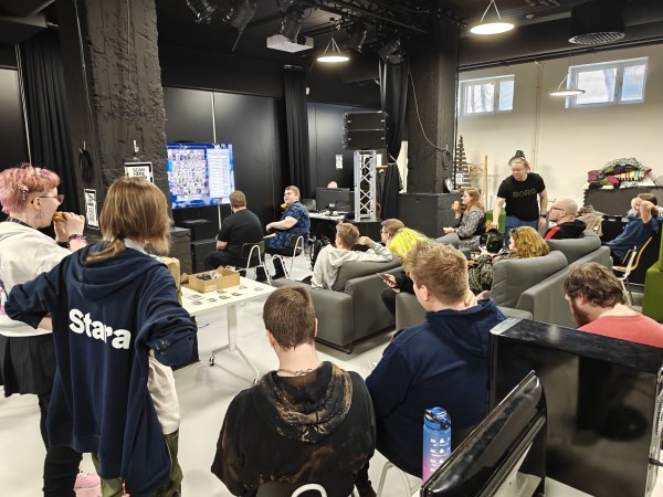 Complete view of GranBlue Versus Rising tournament match setup with players, arcade controller, and streaming display at Lahti Fisticuffs